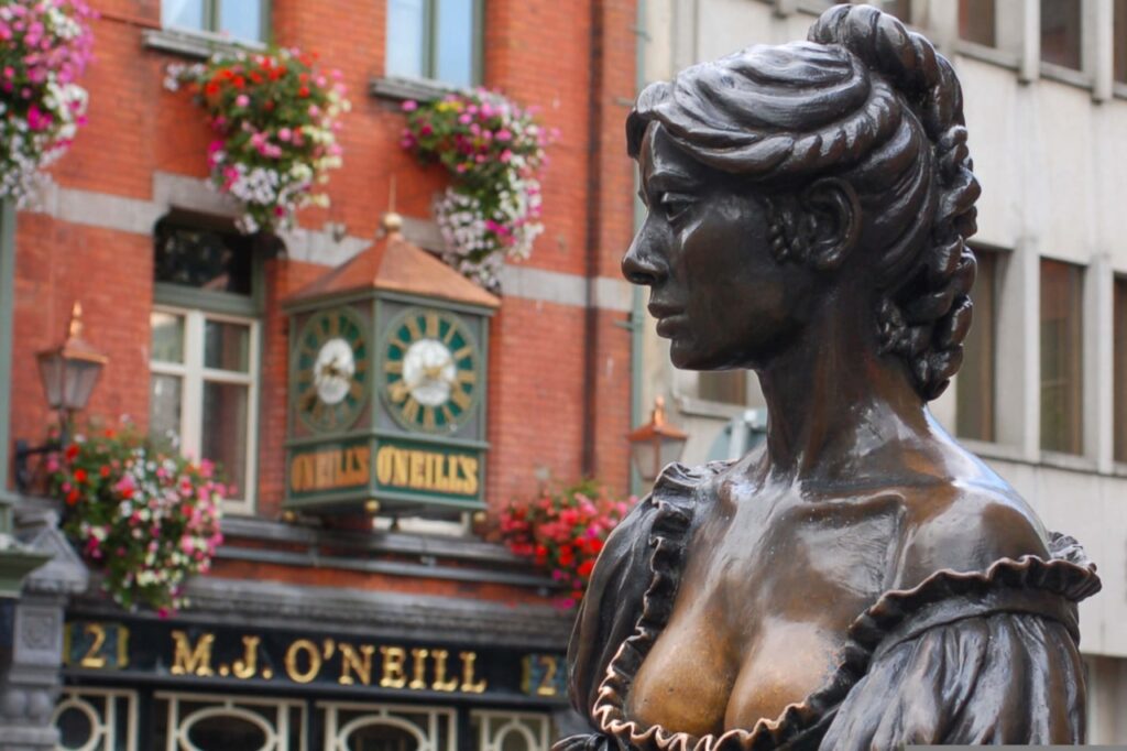 The bronze Molly Malone statue in Dublin, shown in profile in front of a pub facade