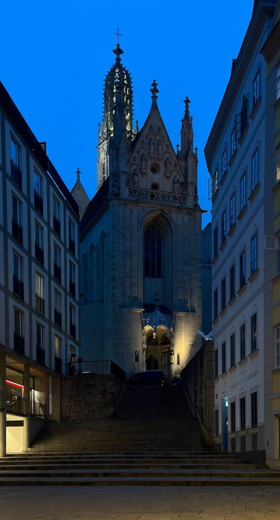 The Gothic church of Maria am Gestade in Vienna above its stone steps at dusk