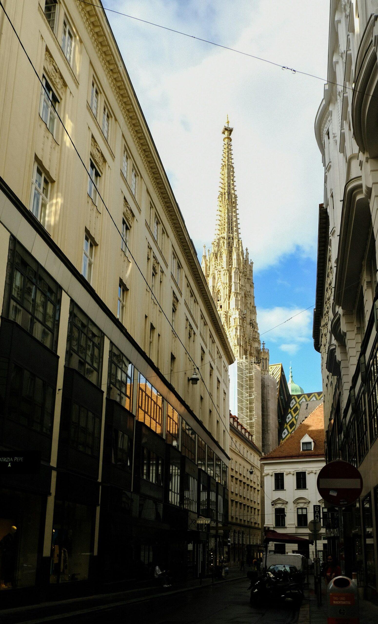 A narrow lane in Vienna's old town with the spire of St Stephen's Cathedral rising behind it