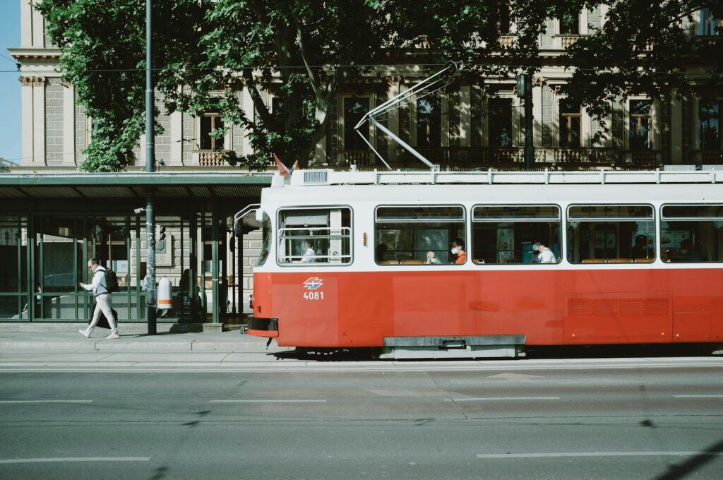 A red Viennese tram passing a nineteenth-century apartment facade in a residential district