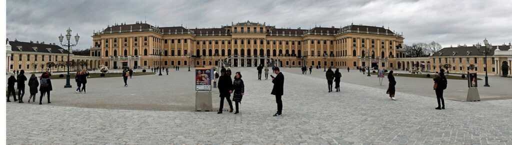 The long yellow facade of Schönbrunn Palace seen across the main courtyard