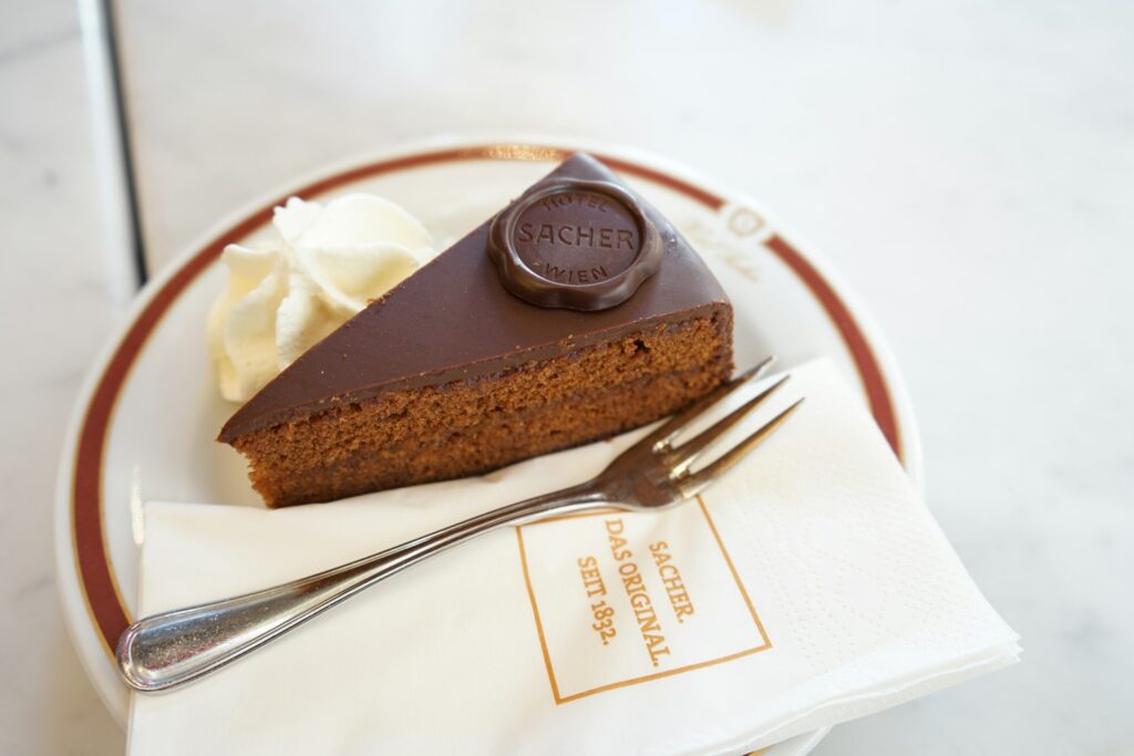Slice of Sachertorte served with a spoonful of unsweetened whipped cream