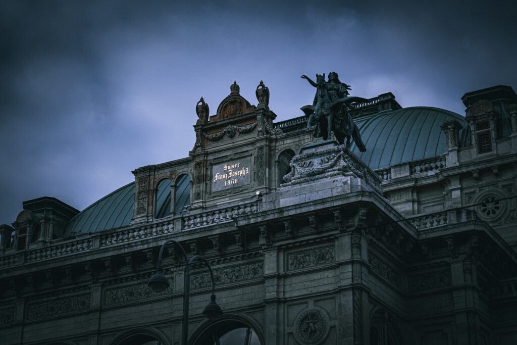 Les statues du toit de l'Opéra national de Vienne se détachant sur un ciel sombre